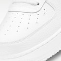 Witte sneaker van generfd leer, close-up van de neus met perforaties en stiksels.