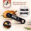 Zwarte digitale thermometer met een display dat 156.3 graden toont, met een geroosterde kip op de achtergrond.