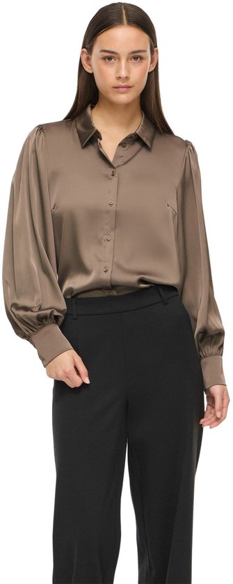 Model in taupe satijnen blouse met pofmouwen en zwarte broek.