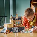 Garçon construisant le château LEGO Harry Potter Poudlard avec la Grande Salle et des figurines.
