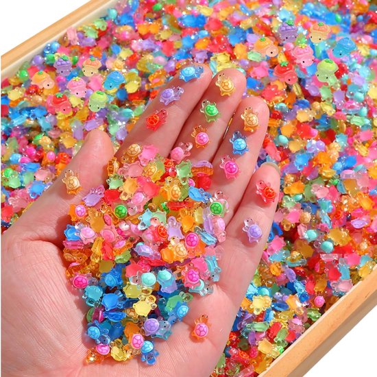 Een hand vol met kleurrijke mini-schildpadjes in plastic. Veelzijdige decoratie, perfect voor knutselen.