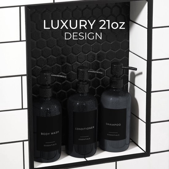 Drie natte, donkergrijze pompdispensers in een mozaïek douche-nis. Labels: BODY WASH, CONDITIONER, SHAMPOO.