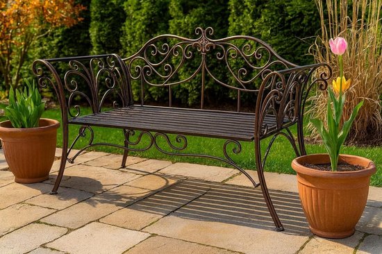 Bronzen tuinbank met sierlijk krulwerk in een tuin met bloempotten.