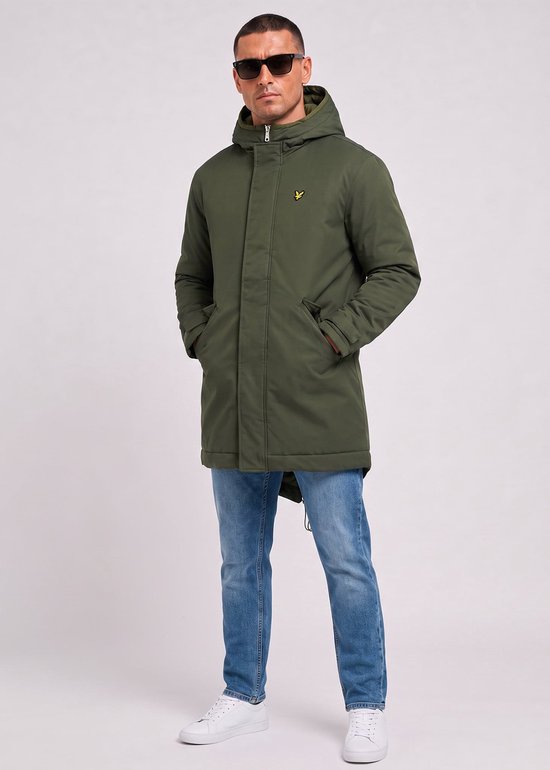Groene parka met capuchon, gele vogel opdruk, doorlopende rits en trekkoord aan de onderkant. Gedragen met spijkerbroek en sneakers.