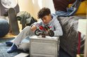 Jongen speelt met LEGO Technic Ducati motorfiets in een slaapkamer.