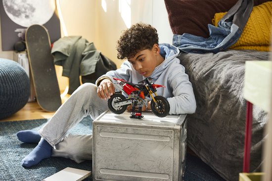 Jongen speelt met LEGO Technic Ducati motorfiets in een slaapkamer.
