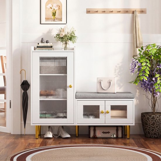 Banc d'entrée blanc avec armoire, banquette et pieds dorés, à côté d'un parapluie et d'une plante.