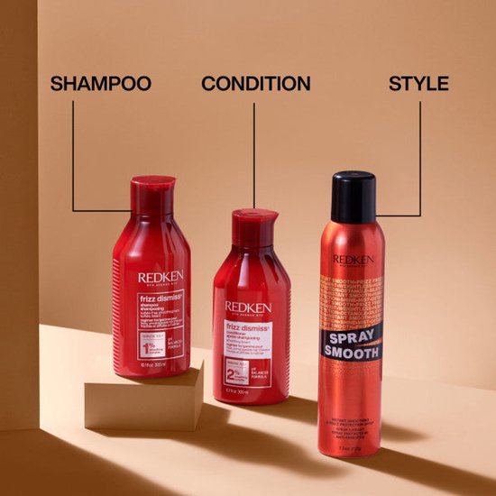 Produits Redken Frizz Dismiss Shampoo, Après-shampooing et Spray Smooth dans des bouteilles rouges.