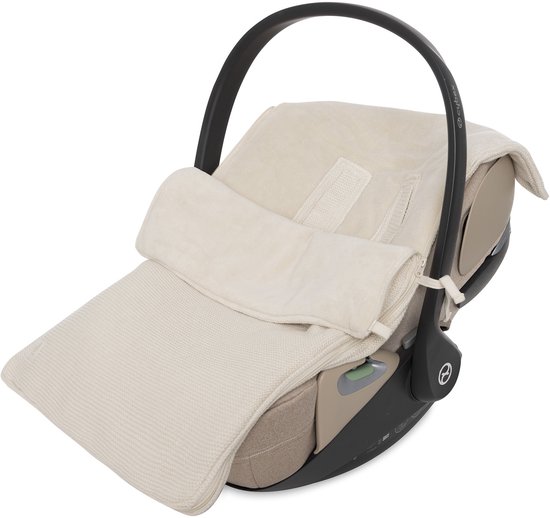 Beige gebreide voetenzak met een bruine rand over een beige autostoel met zwarte draagbeugel.