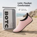 Roze gestreepte waterschoen met zwarte rand, verpakt in BOTC-zak, op zand.