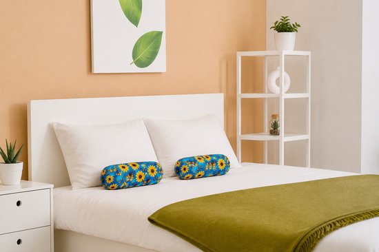 Opgemaakt bed met twee blauwe kussens met bloemenprint.