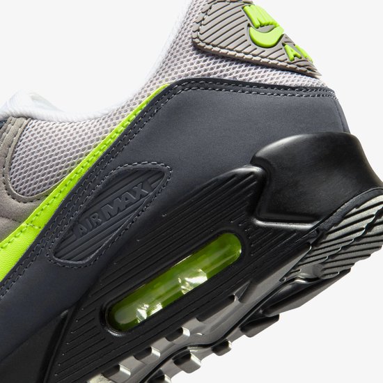 Detail van de hiel van een grijze Nike Air Max 90 sneaker met Air Max logo en neon groene details.