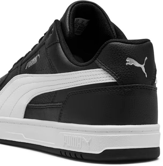 Zij-aanzicht van een zwarte Puma sneaker met witte streep en Puma logo op de hiel.