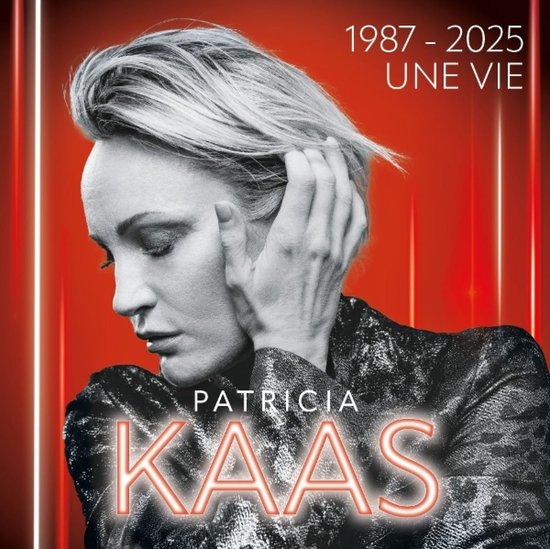 Patricia Kaas, 1987-2025 Une Vie. Portret van Patricia Kaas, met haar hand in haar blonde haar. Ze draagt een zwart jasje met glimmend patroon.