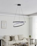 Een zwarte, moderne hanglamp met twee overlappende ringen, hangend boven een bank