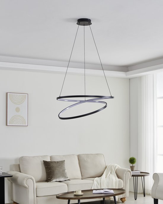 Een zwarte, moderne hanglamp met twee overlappende ringen, hangend boven een bank
