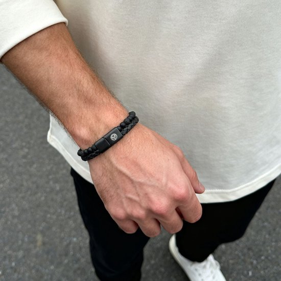 Zwarte lavasteen armband met gevlochten leer en een zilverkleurige sluiting met logo.