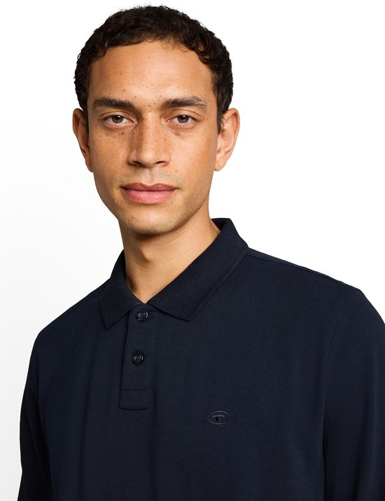 Close-up van een man met een donkerblauw piqué poloshirt met lange mouwen.