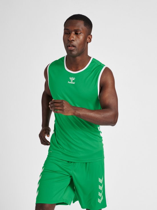 Model in een groene mouwloze sporttop met witte bies en bijpassende korte broek met witte chevrons. Zwarte schoenen en witte sokken.