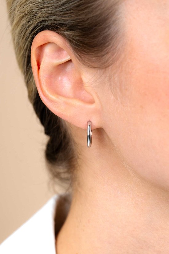 Gladde zilverkleurige oorring van 15 x 2 mm aan een oor.