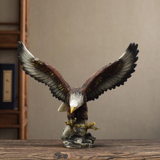 Bruin-witte arend sculptuur met vleugels gespreid op een rots, geplaatst op een houten tafel.