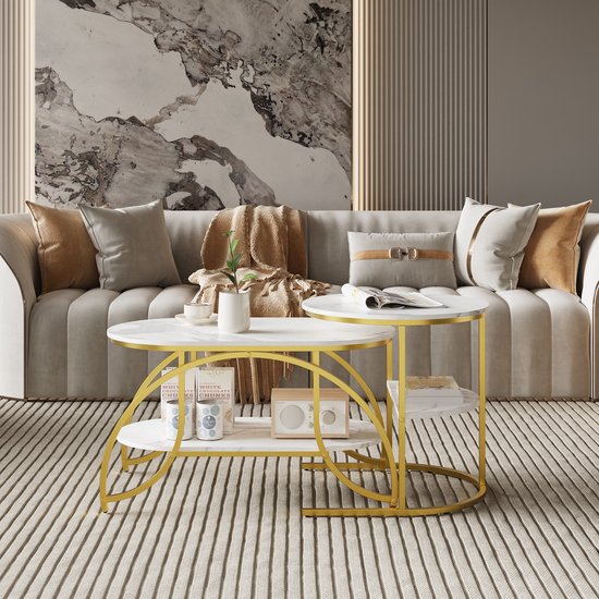 Moderne salontafel set met marmerlook bladen en gouden frame, bij een gestoffeerde bank.
