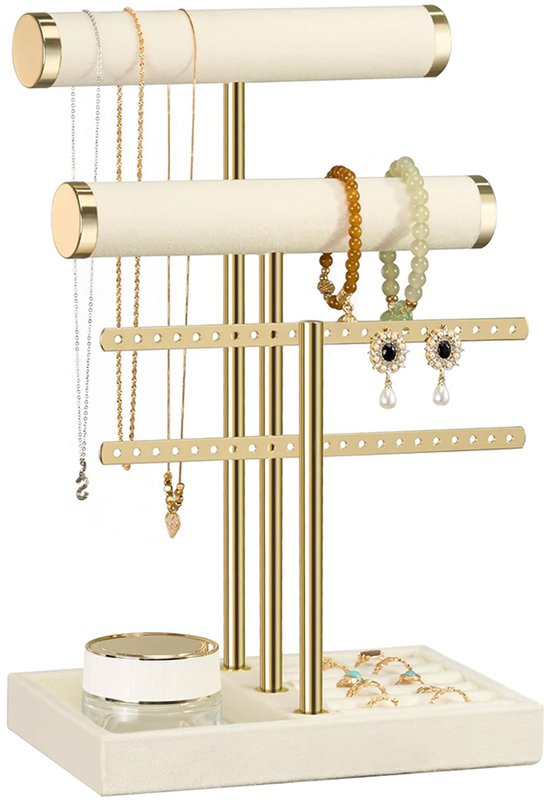 Crèmekleurige fluwelen sieradenhouder met gouden staanders, gevuld met kettingen, armbanden, oorbellen en ringen.