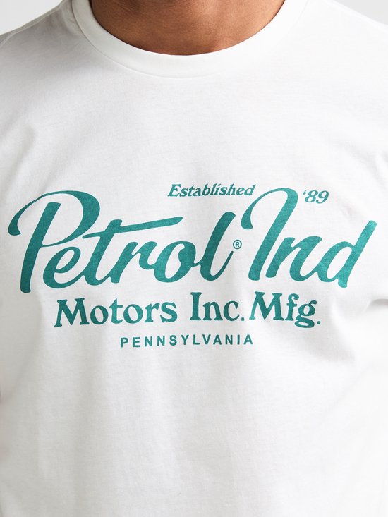 Close-up van wit T-shirt met groenblauwe 'Petrol Ind. Motors Inc. Mfg. Pennsylvania' print.