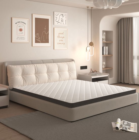 Een wit gewatteerd matras van 160x200 cm ligt op een grijs bed met een gestoffeerd hoofdeinde in een slaapkamer.