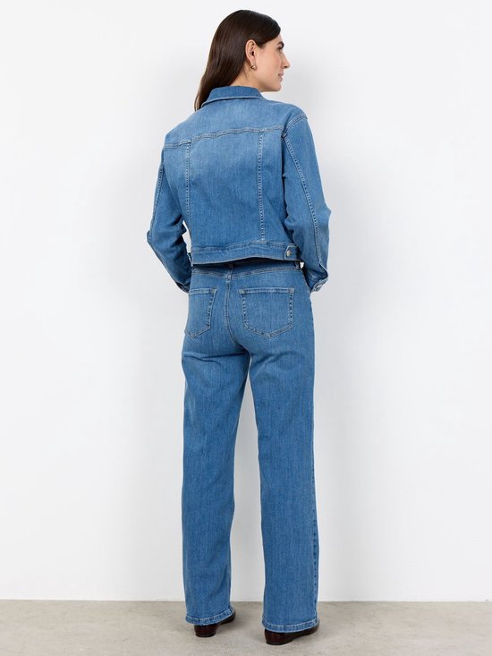 Achteraanzicht van een model in een lichtblauwe spijkerjas en bijpassende jeans met wijde pijpen.