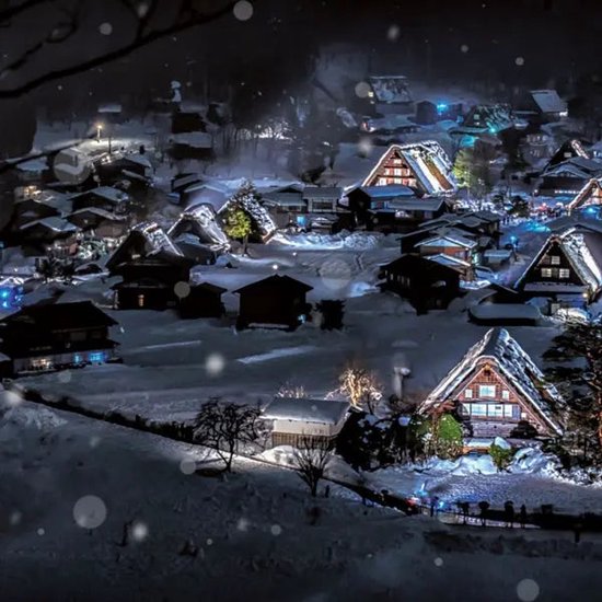 Besneeuwd traditioneel Japans dorp 's nachts met verlichte huizen.