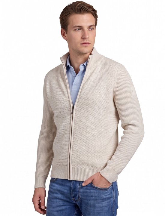 Man met de zijkant naar ons toe, draagt een beige gebreide vest met rits over een lichtblauw poloshirt. De vest heeft lange mouwen en een subtiel textuurpatroon.