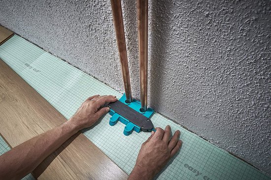 Een wolfcraft contourmal wordt op een houten vloer geplaatst bij koperen buizen in een kamer.