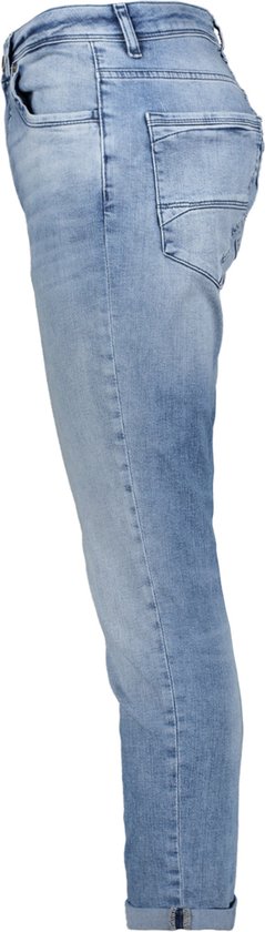 Lichtblauwe jeans, slim fit, opgerolde pijpen, met lichte verouderde plekken, gefotografeerd vanaf de zijkant.