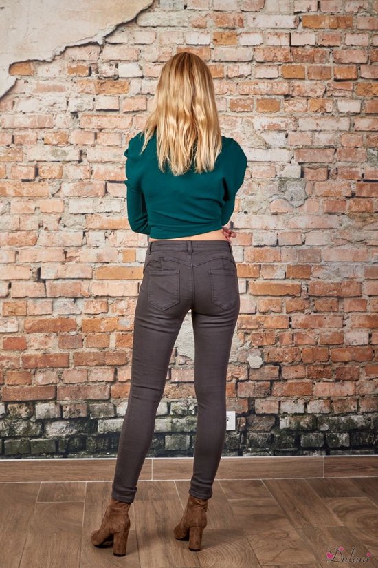 Modèle de dos dans un pantalon push-up gris avec un haut vert foncé.