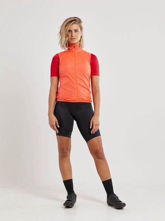 Dames fietsparcours in het oranje met een rits aan de voorkant. Ze draagt een rode fietstop en zwarte fietsbroek.