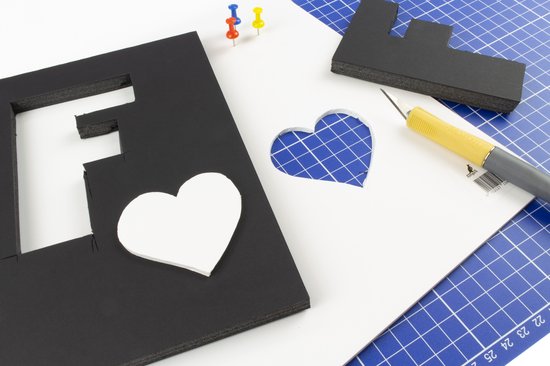 Zwarte letter F van schuimplaat met een uitgesneden hartvorm en een stanley mes.
