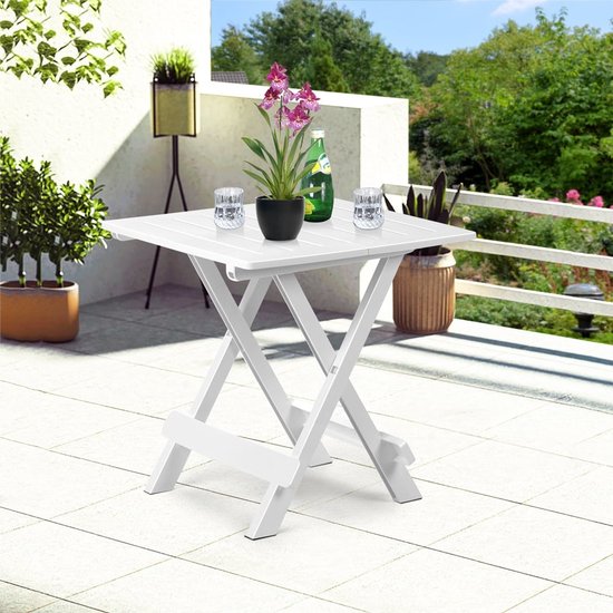 Wit klaptafeltje op een terras met twee glazen, een fles en een plant.