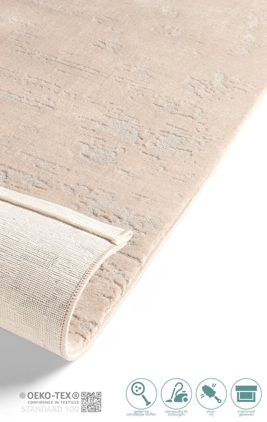 Tapis beige à motif abstrait, enroulé pour montrer le dos.
