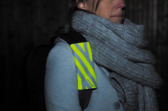 Draagband met gele en grijze reflecterende strepen om de schouder van een jas gedragen.