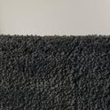 Gros plan sur le tissu pelucheux, gris foncé, du tapis de bain.