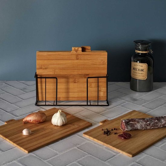 Bamboe snijplankenset in zwarte houder met twee losse snijplanken. Op de losse planken liggen ui, knoflook en salami.