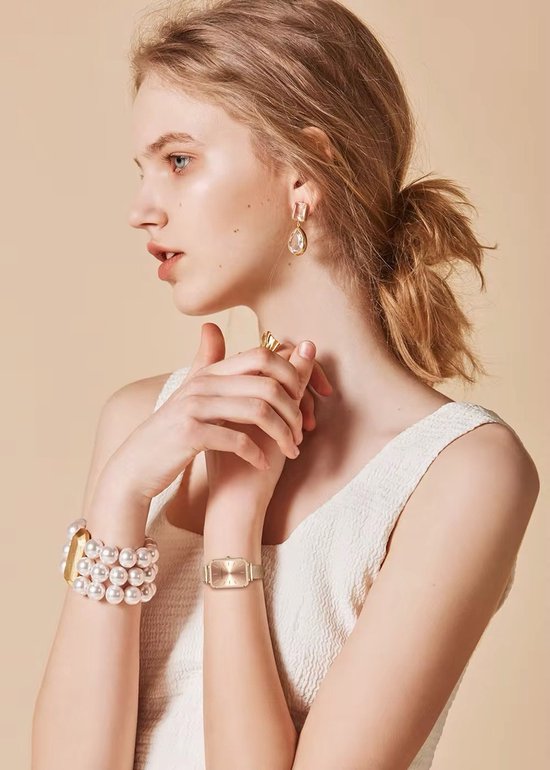 Mannequin portant une montre dorée avec cadran rectangulaire et bracelet en maille, bracelet de perles.