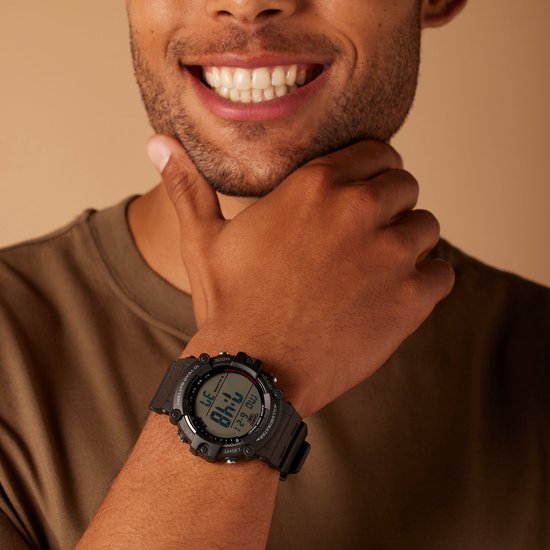 Een man met een bruin T-shirt draagt een zwart Casio digitaal horloge met de datum MA 6-21.
