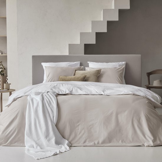 Grande housse de couette beige avec un plaid tricoté blanc dessus.