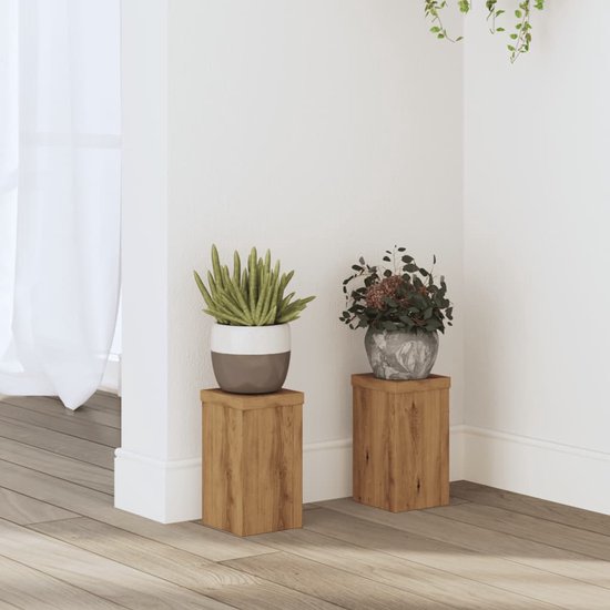 Twee houten kubusplantenstandaards, één met een groene plant, één met bloemen, op een houten vloer.