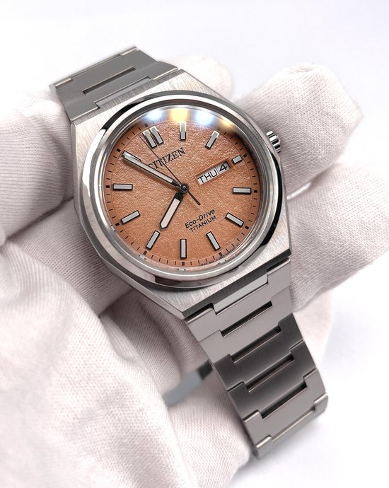 Zilverkleurig titanium horloge met perzikkleurige wijzerplaat. Dag en datum venster zichtbaar.