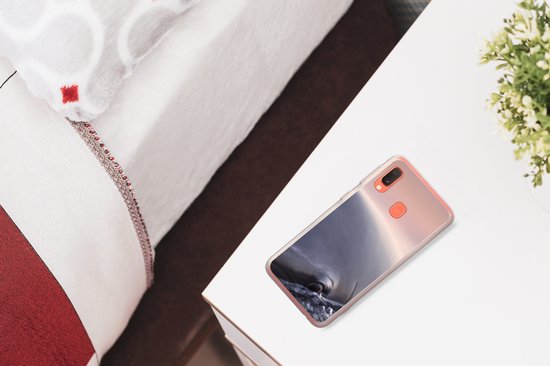 Transparante hoes met dolfijnprint op telefoon, naast bed en plantje.