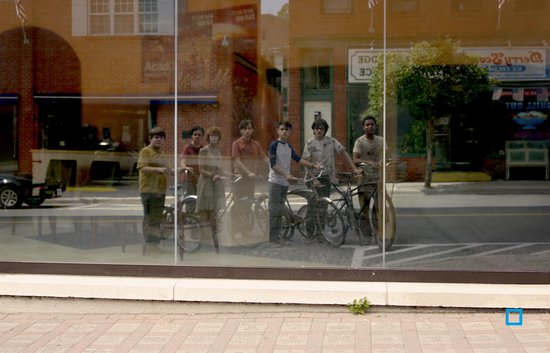 De reflectie van zeven personen met fietsen in een etalage.