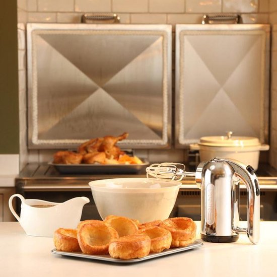 Chrome Dualit handmixer op een aanrecht met Yorkshire puddings, een gebraden kip en een sauskom.